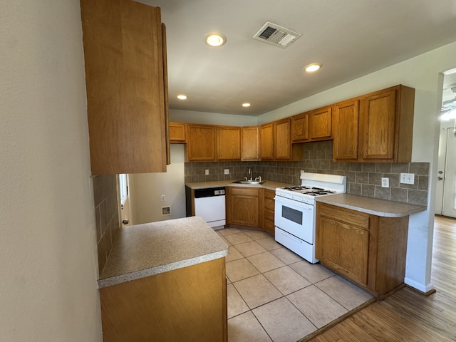 216 Gale St, Houston, TX 77009 - kitchen with white appliances, a sink, brown cabinets, tasteful backsplash, and recessed lighting