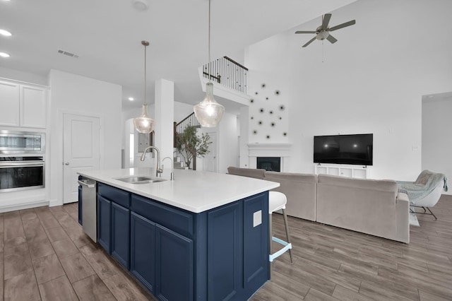 2807 Kingly Pine Trl, Conroe, TX 77385 - kitchen featuring blue cabinetry, stainless steel appliances, a sink, ceiling fan, and light wood-type flooring