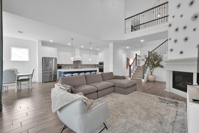 2807 Kingly Pine Trl, Conroe, TX 77385 - living room with stairway, wood finished floors, a glass covered fireplace, baseboards, and recessed lighting