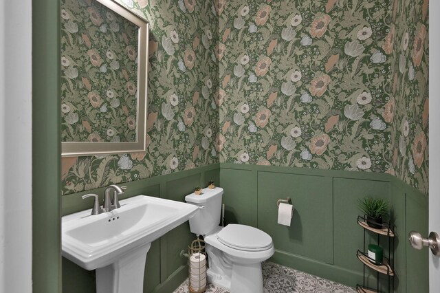 2807 Kingly Pine Trl, Conroe, TX 77385 - bathroom with wallpapered walls, a wainscoted wall, toilet, a sink, and a decorative wall
