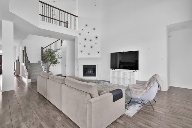 2807 Kingly Pine Trl, Conroe, TX 77385 - living area featuring stairs, wood finished floors, a towering ceiling, and a glass covered fireplace