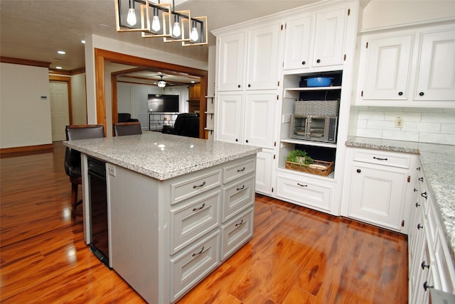 15007 Pebble Bend Dr, Houston, TX 77068 - kitchen featuring wood finished floors, white cabinets, a kitchen island, tasteful backsplash, and recessed lighting