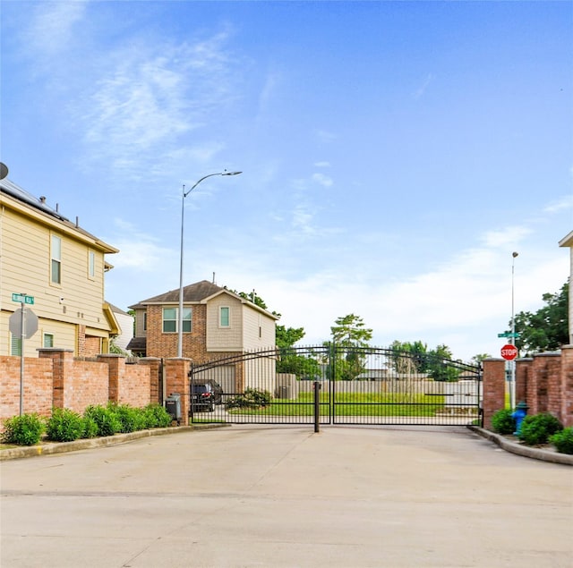 8038 Villa Lago Ln, Houston, TX 77070 - view of concrete street featuring traffic signs, a gate, curbs, and street lights