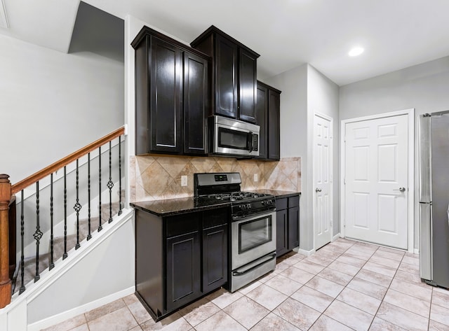 8038 Villa Lago Ln, Houston, TX 77070 - kitchen with appliances with stainless steel finishes, decorative backsplash, dark cabinetry, dark stone counters, and light tile patterned floors
