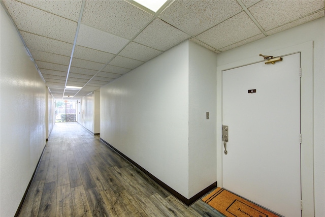 hallway with a paneled ceiling and wood finished floors