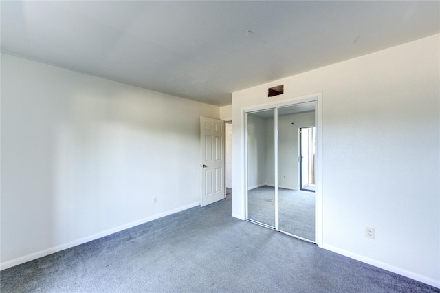 unfurnished bedroom with dark colored carpet, baseboards, and a closet