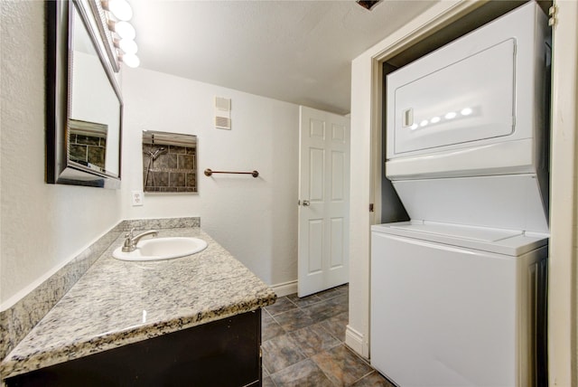 laundry room featuring stacked washer / dryer and baseboards