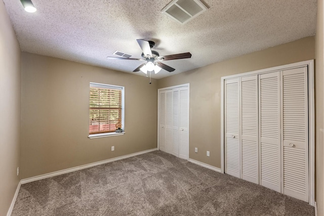 304 Inverness St, Huntsville, TX 77340 - unfurnished bedroom with multiple closets, carpet floors, baseboards, ceiling fan, and a textured ceiling