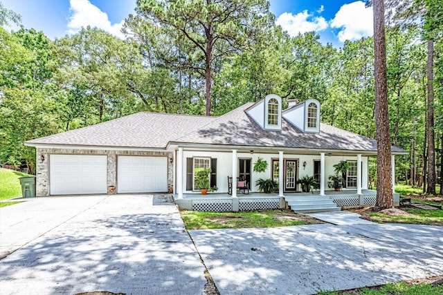 304 Inverness St, Huntsville, TX 77340 - view of front of house featuring a porch, concrete driveway, an attached garage, a shingled roof, and stucco siding