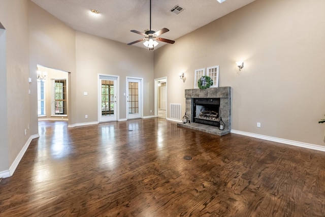 304 Inverness St, Huntsville, TX 77340 - unfurnished living room featuring a ceiling fan, a tile fireplace, baseboards, dark wood finished floors, and a towering ceiling