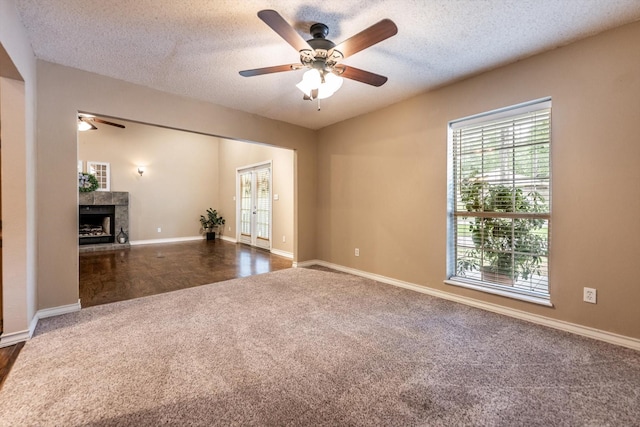 304 Inverness St, Huntsville, TX 77340 - unfurnished living room with ceiling fan, dark colored carpet, plenty of natural light, a fireplace with raised hearth, and a textured ceiling