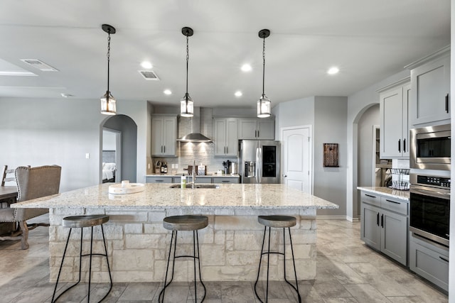 192 Primrose Path, Canyon Lake, TX 78133 - kitchen with stainless steel appliances, gray cabinetry, wall chimney range hood, arched walkways, and a sink