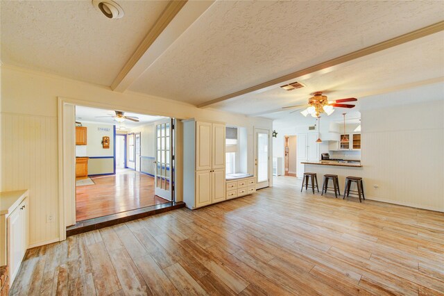 22211 Bucktrout Ln, Katy, TX 77449 - unfurnished living room with ceiling fan, a textured ceiling, beam ceiling, light wood-style flooring, and baseboards