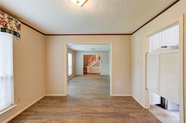 22211 Bucktrout Ln, Katy, TX 77449 - corridor with wood finished floors, crown molding, stairway, a textured ceiling, and baseboards