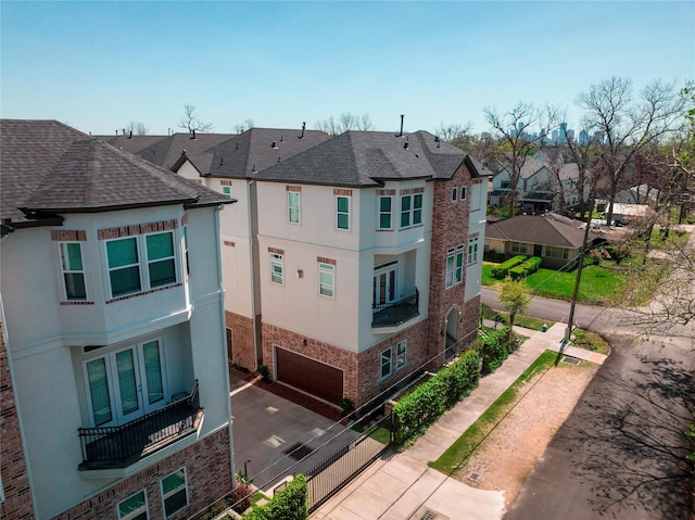 view of property exterior with a residential view, stucco siding, a garage, and brick siding