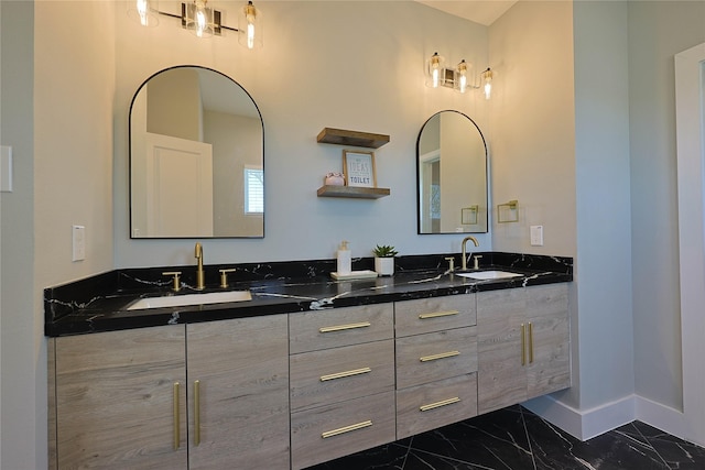 bathroom featuring marble finish flooring, double vanity, and baseboards