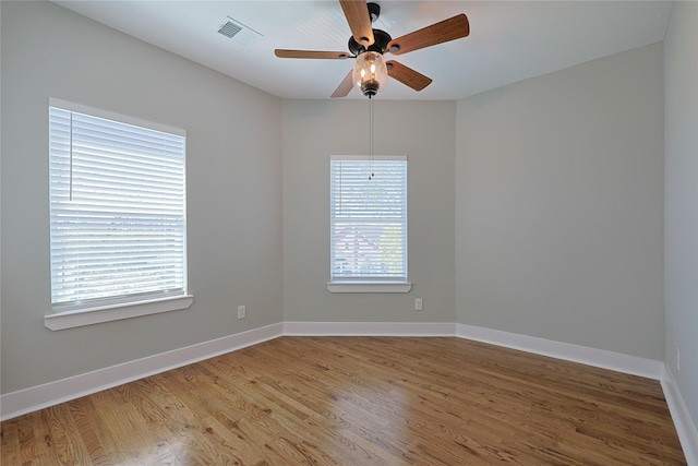 empty room with light wood finished floors, a ceiling fan, and baseboards