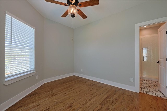 spare room featuring wood finished floors, a ceiling fan, and baseboards