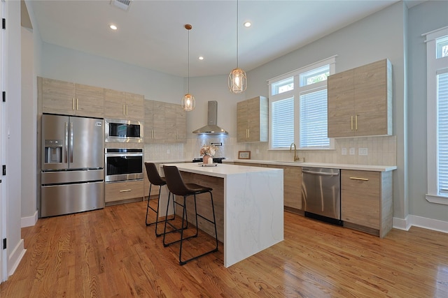 kitchen featuring stainless steel appliances, a sink, modern cabinets, a breakfast bar area, and light countertops