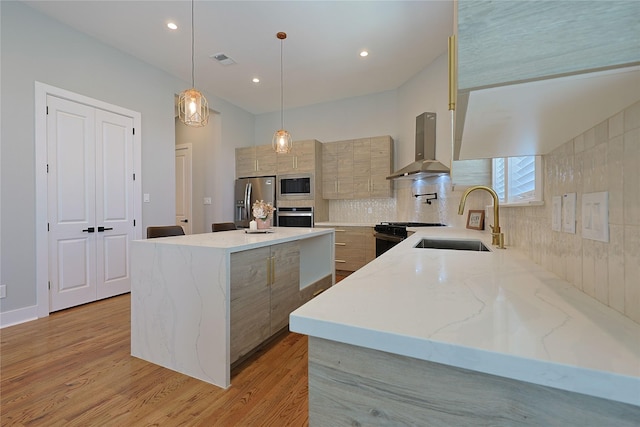 kitchen with wall chimney exhaust hood, stainless steel appliances, a sink, modern cabinets, and a center island