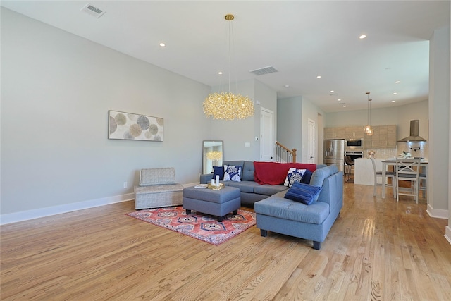 living room with light wood finished floors, stairs, recessed lighting, a chandelier, and baseboards
