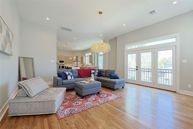 living area with wood finished floors, baseboards, recessed lighting, french doors, and a chandelier