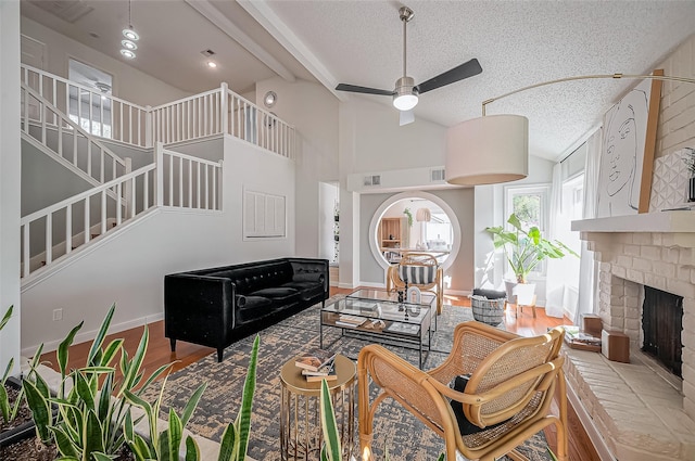 2215 Braesmeadow Ln, Sugar Land, TX 77479 - living room with a ceiling fan, stairway, a brick fireplace, a textured ceiling, and wood finished floors