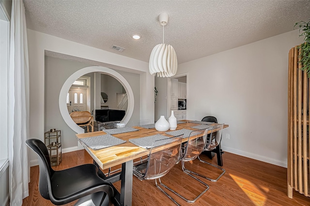 2215 Braesmeadow Ln, Sugar Land, TX 77479 - dining room with baseboards, wood finished floors, a textured ceiling, and arched walkways