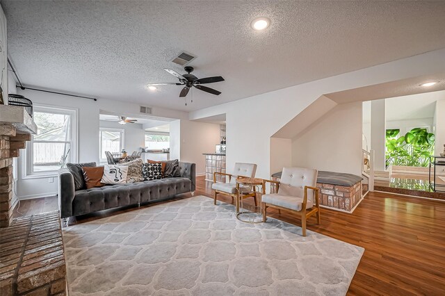 2215 Braesmeadow Ln, Sugar Land, TX 77479 - living room featuring a textured ceiling, wood finished floors, a ceiling fan, a brick fireplace, and recessed lighting