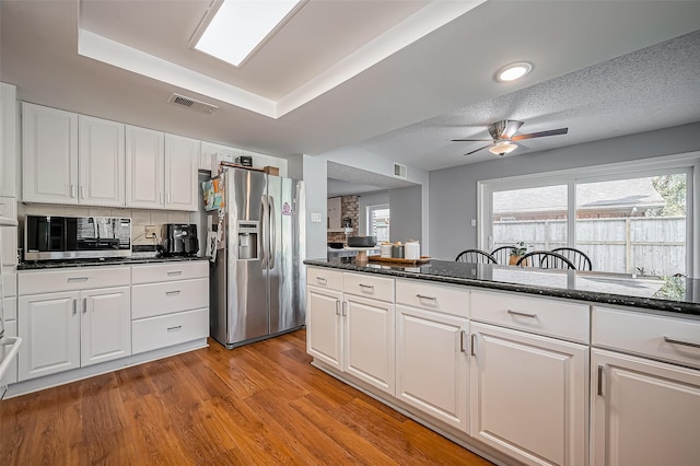 2215 Braesmeadow Ln, Sugar Land, TX 77479 - kitchen featuring stainless steel appliances, a ceiling fan, white cabinets, light wood-type flooring, and decorative backsplash