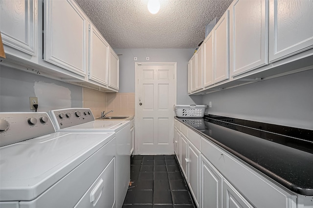 2215 Braesmeadow Ln, Sugar Land, TX 77479 - clothes washing area featuring washing machine and dryer, dark tile patterned flooring, a textured ceiling, and cabinet space