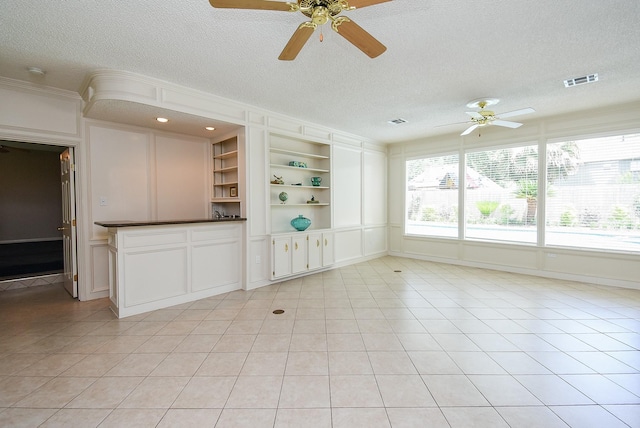 13602 Wendelyn Ln, Houston, TX 77069 - unfurnished living room featuring ceiling fan, a textured ceiling, light tile patterned floors, built in shelves, and ornamental molding
