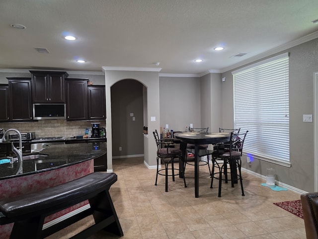 dining area with crown molding, arched walkways, baseboards, recessed lighting, and light tile patterned flooring