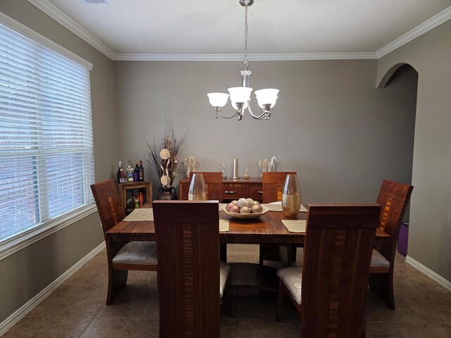 dining area with a chandelier, arched walkways, tile patterned flooring, ornamental molding, and baseboards
