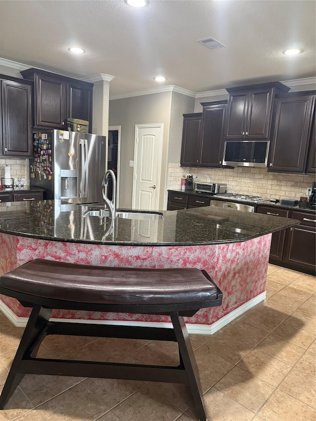 kitchen featuring appliances with stainless steel finishes, a kitchen bar, ornamental molding, a sink, and tasteful backsplash