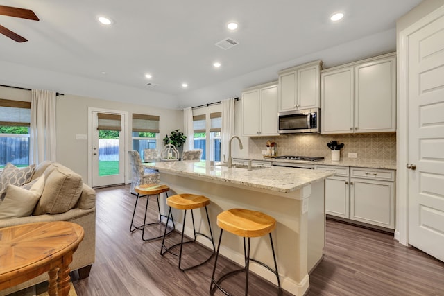 21310 Baldovin Way, Tomball, TX 77375 - kitchen featuring stainless steel appliances, a sink, backsplash, light stone countertops, and a kitchen breakfast bar