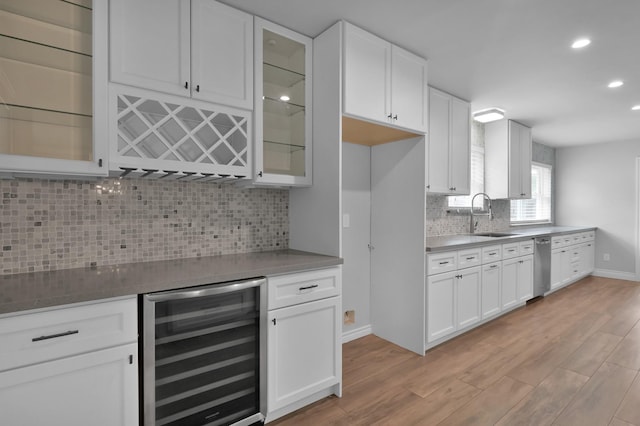 2806 Triway Ln, Houston, TX 77043 - kitchen featuring beverage cooler, a sink, stainless steel dishwasher, light wood-style floors, and white cabinets