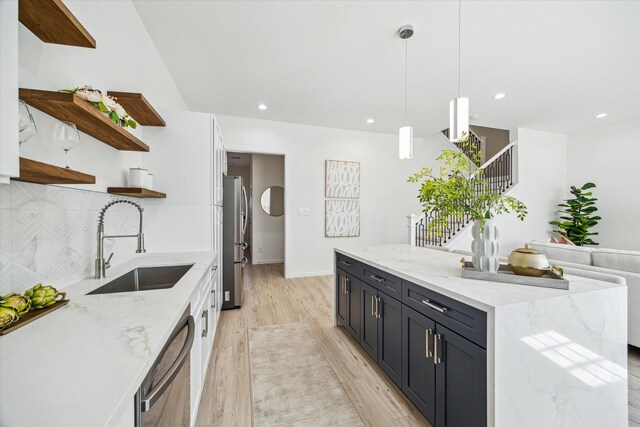 927 Bianco Ln, Houston, TX 77091 - kitchen featuring open shelves, appliances with stainless steel finishes, light wood-style flooring, a sink, and decorative backsplash