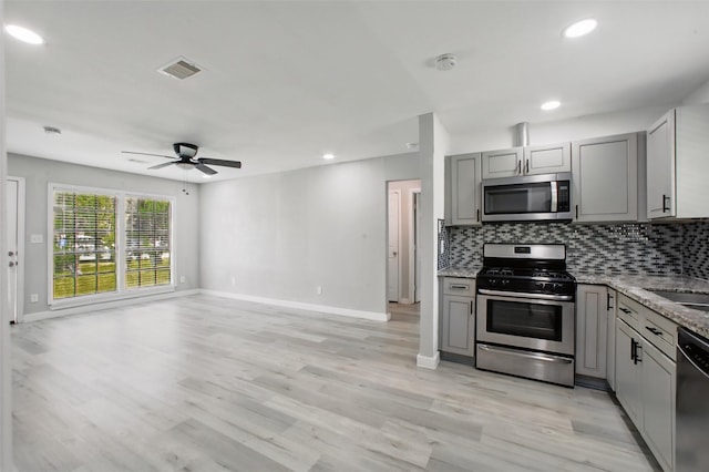 3221 Texas Ave, Texas City, TX 77590 - kitchen with stainless steel appliances, gray cabinetry, decorative backsplash, light stone countertops, and recessed lighting