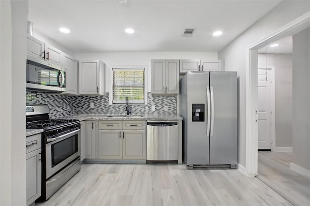 3221 Texas Ave, Texas City, TX 77590 - kitchen with stainless steel appliances, light wood finished floors, decorative backsplash, gray cabinets, and light stone countertops