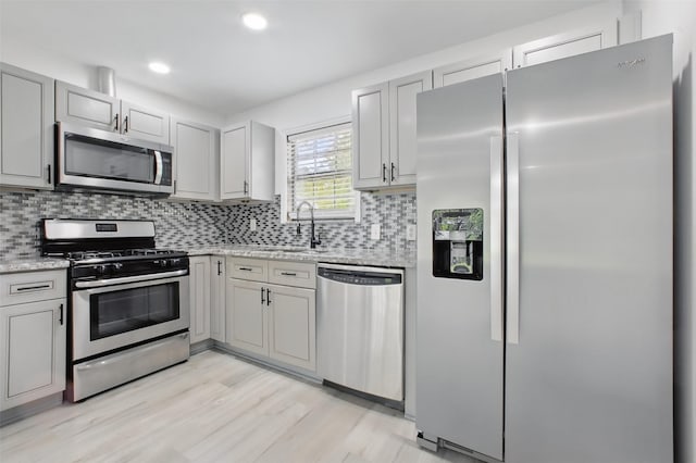 3221 Texas Ave, Texas City, TX 77590 - kitchen with appliances with stainless steel finishes, backsplash, light wood finished floors, light stone countertops, and recessed lighting