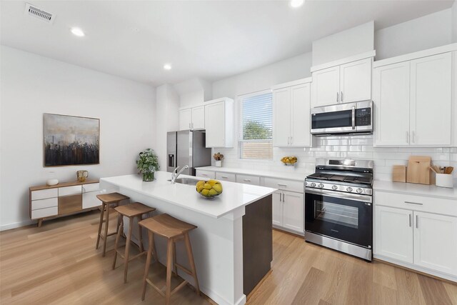 1013 Erin St Unit R, Houston, TX 77009 - kitchen featuring appliances with stainless steel finishes, a sink, tasteful backsplash, light wood-type flooring, and recessed lighting