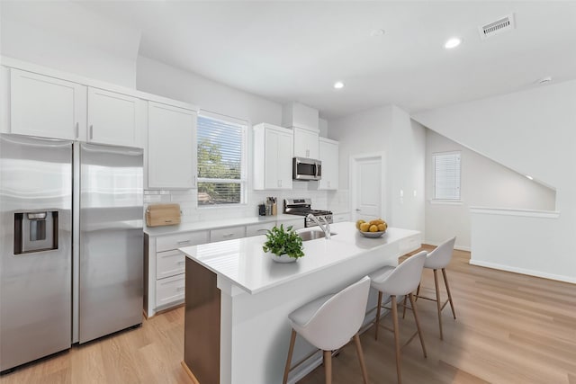 1013 Erin St Unit R, Houston, TX 77009 - kitchen with appliances with stainless steel finishes, tasteful backsplash, a breakfast bar, light wood-type flooring, and a sink