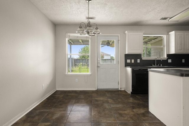 kitchen featuring white cabinets, dark countertops, a chandelier, a textured ceiling, and a sink