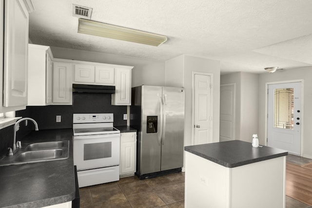 kitchen with stainless steel fridge, white range with electric cooktop, a sink, under cabinet range hood, and dark countertops
