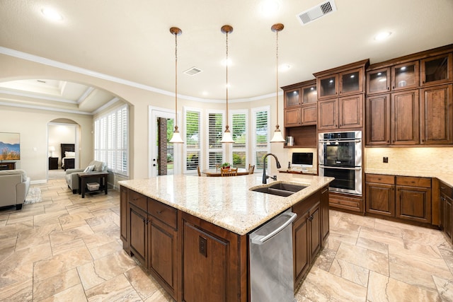 kitchen with stainless steel appliances, a sink, arched walkways, stone tile floors, and crown molding