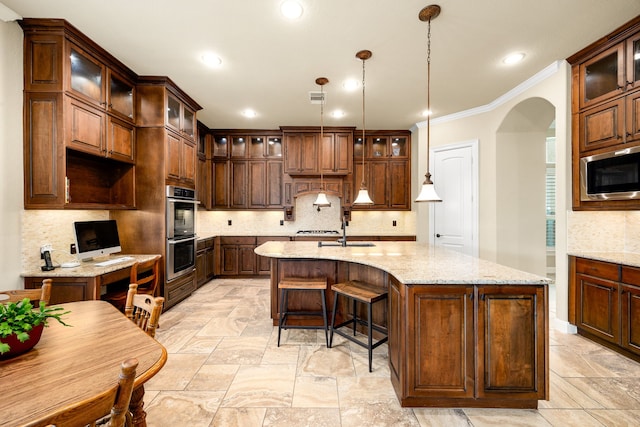 kitchen featuring stainless steel appliances, ornamental molding, decorative backsplash, an island with sink, and arched walkways