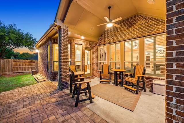 patio terrace at dusk featuring fence and ceiling fan