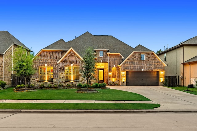 view of front of house with brick siding, concrete driveway, a front yard, and a shingled roof
