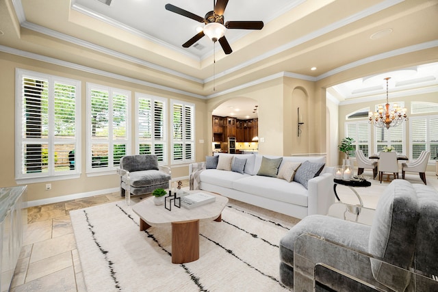 living area featuring a raised ceiling, crown molding, arched walkways, a chandelier, and ceiling fan